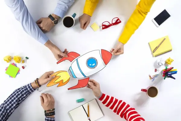 Equipo colaborando para armar una maqueta de un cohete en una mesa, impulsando estrategias digitales.