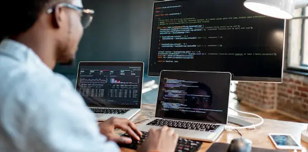 Mantenimiento de software: ingeniero depurando código en una oficina moderna.