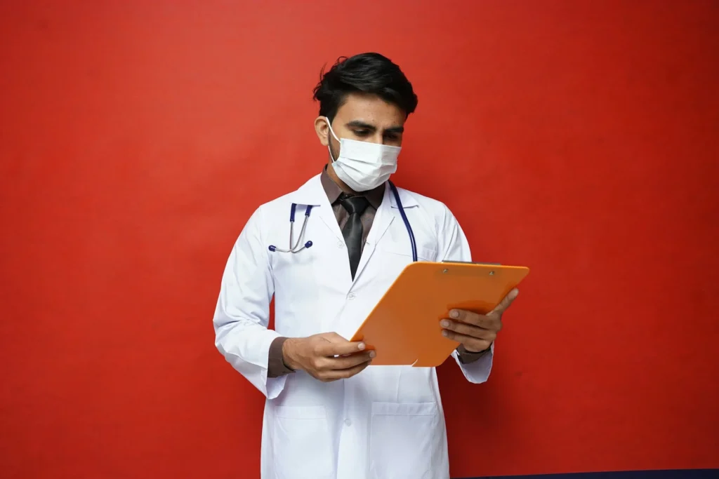 Médico con mascarilla, leyendo un expediente en una consulta médica, ilustrando el impacto de la tecnología 5G en la industria de la salud para mejorar la atención y el acceso a la información.