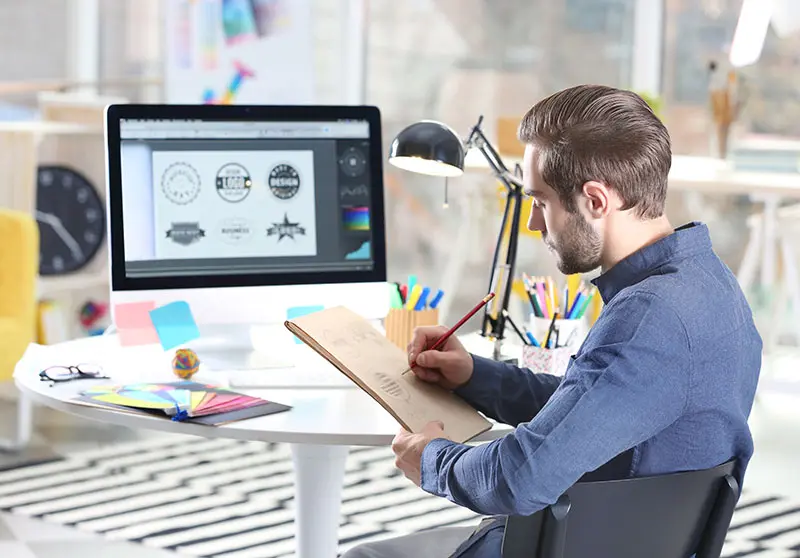 Persona dentro de una agencia de diseño grafico diseñando y pensando que hacer